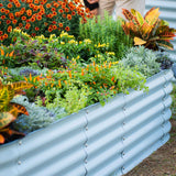 Metal raised garden bed with a variety of colorful plants and flowers.