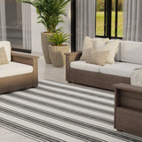 Outdoor patio with wooden furniture, striped rug, and potted plants.