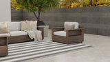 Outdoor patio furniture set with a sofa and armchair on a striped rug.