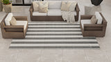 Outdoor furniture set with striped rug on a tiled patio