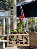 Decorative hanging planter with a red flower in an outdoor setting