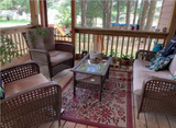 Outdoor patio with wicker furniture, Wildflowers Cranberry rug and a coffee table on a wooden deck.