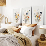 Cozy bedroom with Neutral Watercolor Wildflower Art Prints Set, pillows, and a lamp.