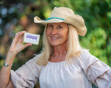 Woman holding a 'Good Life' product in front of a green blurred background