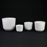 Set of white ceramic cups of different sizes on a black background