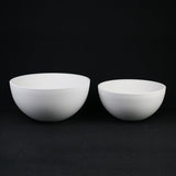 Two white ceramic bowls on a black background