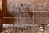 Set of metal fireplace tools against a wooden wall.