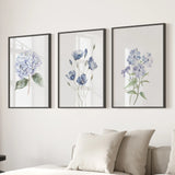 Three framed floral prints on a wall above a sofa with pillows.