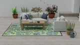 Living room with a Wildflowers Eggplant floral rug, sofa, coffee table, and decorative plants.