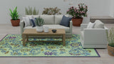 Living room with a floral Wildflowers Eggplant rug, white sofa, and wooden coffee table.