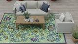 Living room with a floral Wildflowers Eggplant rug, white sofa, and wooden coffee table.