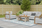 Outdoor patio set with sofa, armchair, and coffee table on a wooden deck.