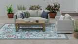 Living room with white sofa, wooden coffee table, and decorative plants on a patterned Wildflowers Stone Terra rug.