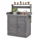 A gray wooden garden utility cabinet with a slatted double door, top shelf, and metal work surface, shown on a white background with decorative plants, pots, and gardening tools.
