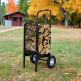 Black metal log carrier with stacked firewood in an outdoor setting with trees and a small building.