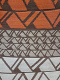 Textile with geometric pattern of triangles in orange, brown, and gray.