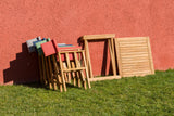 Wooden outdoor furniture set against a red wall on grass
