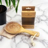 Bamboo hair brush with packaging on a marble surface
