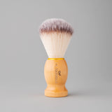 Shaving brush with wooden handle and synthetic bristles on a gray background