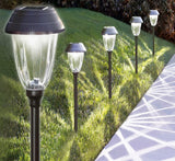 Set of solar-powered garden lights on a grassy area next to a pathway.