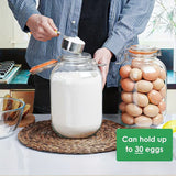 Person using a jar with a lid, next to a container of eggs on a kitchen counter.