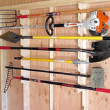 Set of gardening tools including a rake, spade, and hedge trimmer on a wooden wall rack.