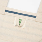 Close-up of a beige fabric with a blue stripe and a label on a white background