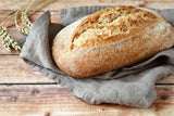 Loaf of bread on a wooden surface with a gray cloth