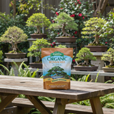 Espoma Organic Bonsai Mix packaging on a wooden table with bonsai trees in the background