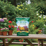 Bag of Espoma Organic Peat Moss on a wooden table with potted flowers in a garden setting