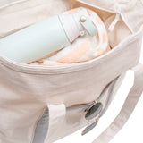Light blue water bottle and sunglasses inside a beige bag on a white background