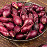 Red onion sets in a bowl on a wooden surface