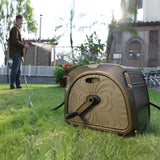 Garden hose reel on grass with a person using a hose in the background