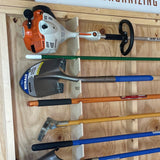 Set of gardening tools including a hedge trimmer and shovels on a wooden surface.