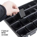Black plastic seedling tray with compartments, held by a hand, on a white background.