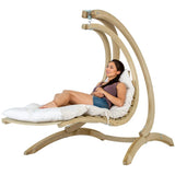 Woman relaxing in a wooden hanging chair with white cushion on a white background