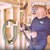 Man organizing garden hoses in a wooden shed.