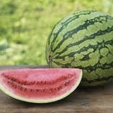 Organic Heirloom Crimson Sweet Watermelon with a slice cut out on a wooden surface