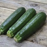 Three Organic Heirloom Dark Green Zucchini on a wooden surface
