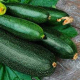 Organic Heirloom Fordhook Zucchinis on a wooden surface with leaves