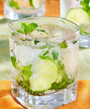 Glass of mojito with lime and mint on an orange napkin