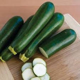 Organic Heirloom Dark Green Zucchini on a wooden cutting board with slices of zucchini.