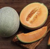Heirloom Organic Hale's Best Jumbo Cantaloupe, one whole and one sliced, on a wooden cutting board.