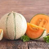 Two Heirloom Organic Edisto Cantaloupe with one cut open on a wooden surface