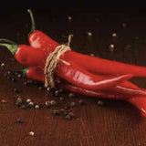 Red chili peppers on a dark surface with peppercorns