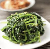 Steamed Heirloom Organic Whale Spinachon a white plate with a blurred background
