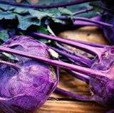 Heirloom Organic Azur Star Kohlrabion a wooden surface with green leaves.