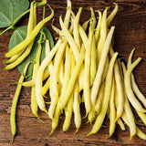 Heirloom Organic Yellow Pencil Pod Bush Beans on a wooden surface with green leaves