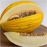 Halved yellow melon on a wooden surface with a neutral background