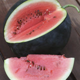 Halved Organic Heirloom Blacktail Mountain Watermelon on a wooden surface